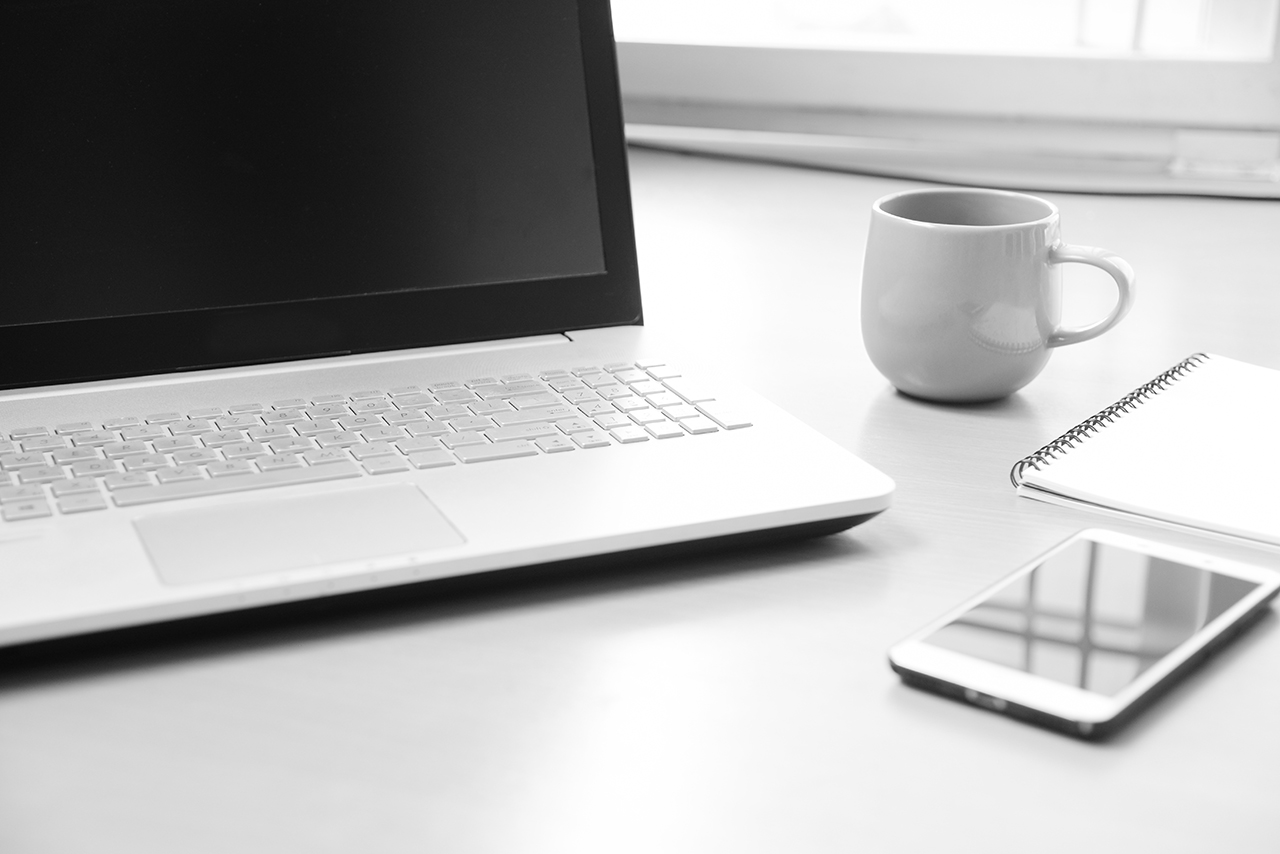 Business Notebook computer with smart phone , notebook paper for note message and a cup of coffee on wood desk background